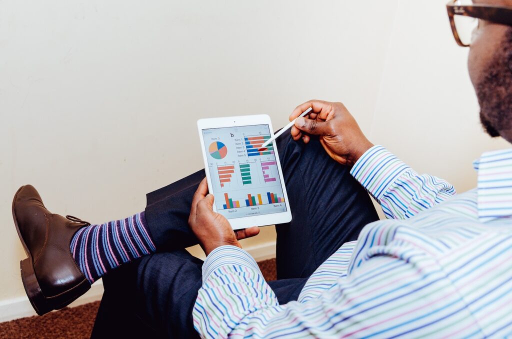 Man sitting in chair looking at financial reports on tablet.